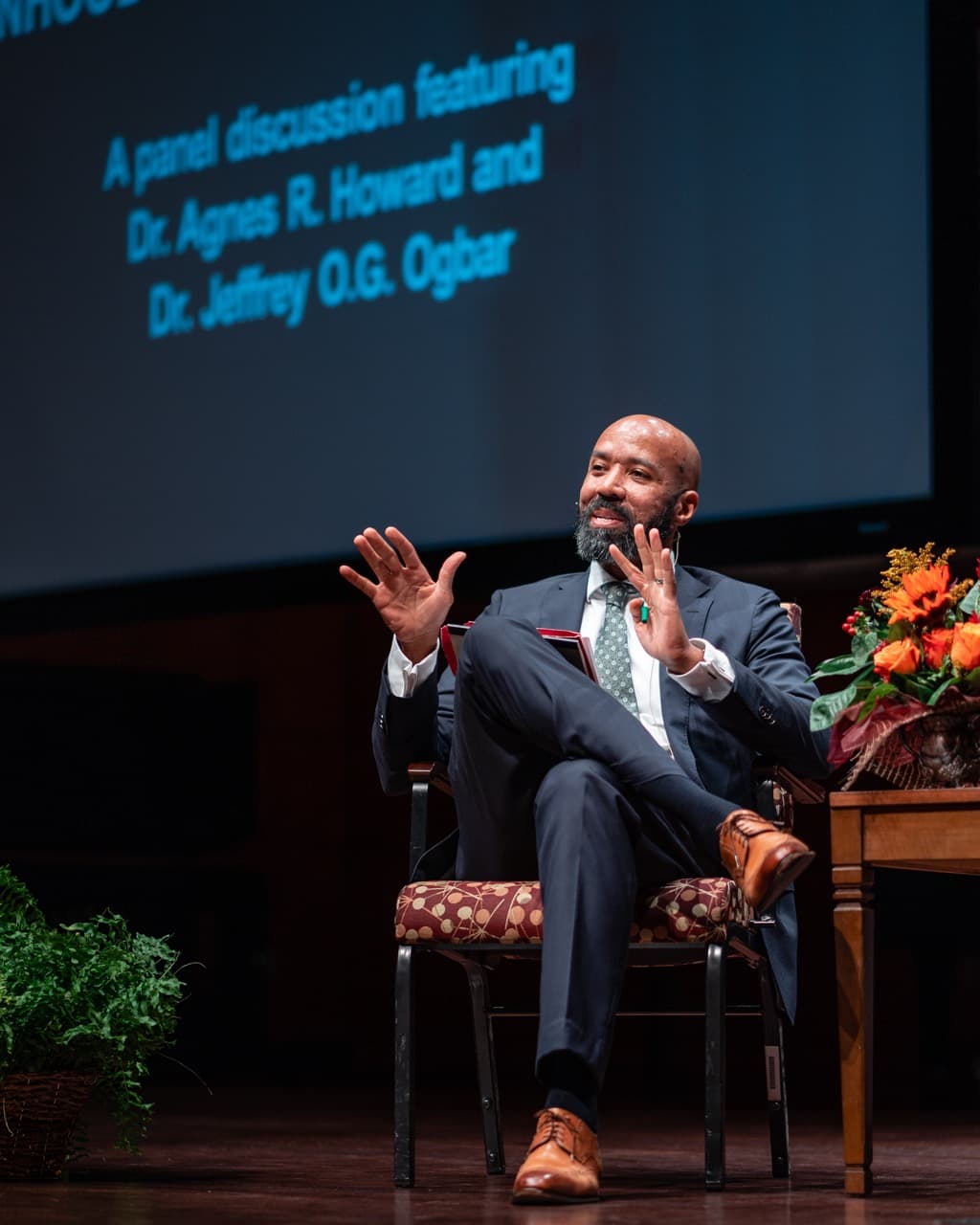 Speaker presenting at professional conference on stage with presentation screen