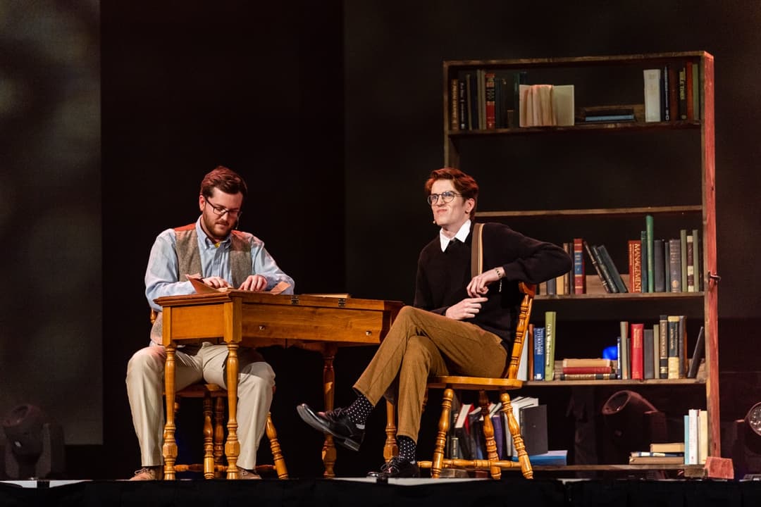 Literary discussion panel with speakers seated at wooden desk in library setting