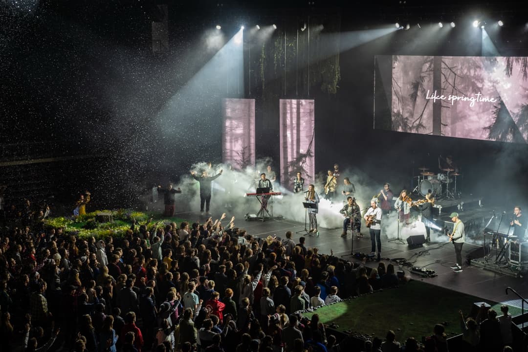 Large concert venue with crowd watching performers on illuminated stage