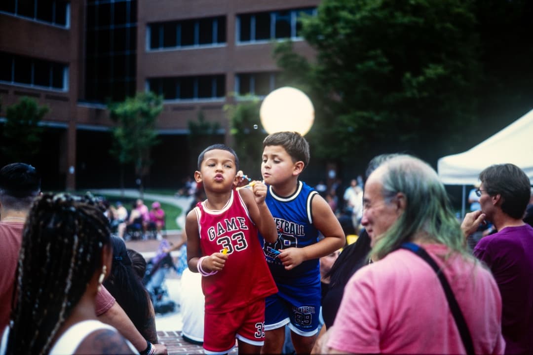 Community festival scene with children in sports jerseys interacting with attendees
