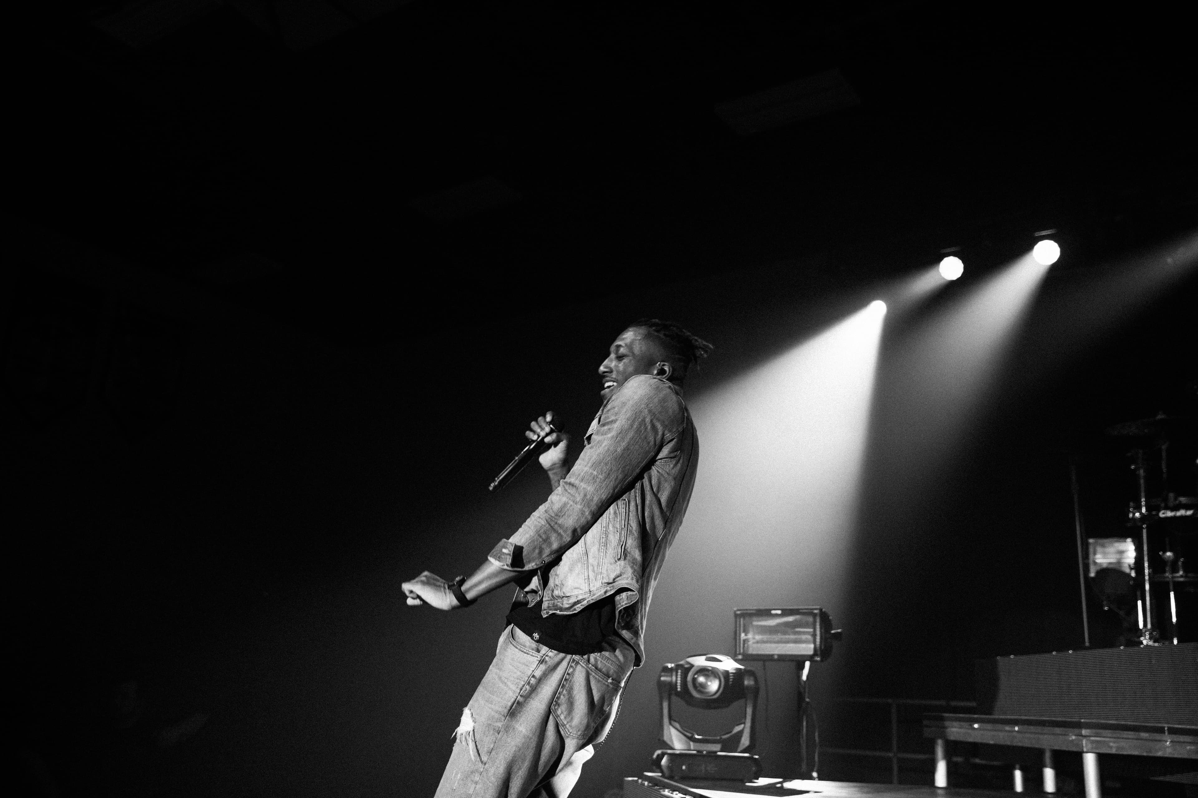 Dramatic black and white concert photography of performer in spotlight