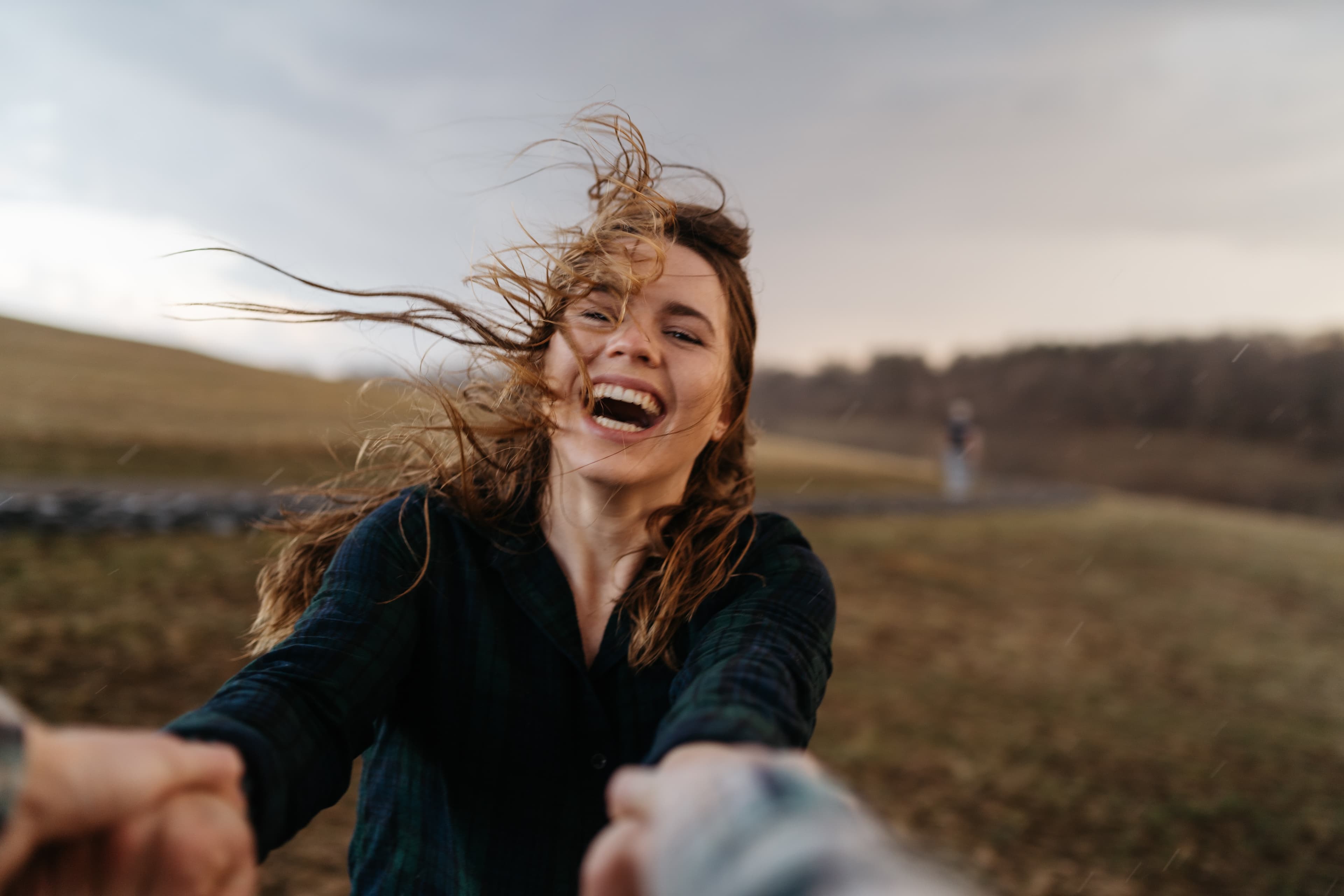 Candid portrait of person laughing with windswept hair during golden hour